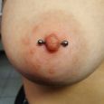 A single breast piercing with a bar