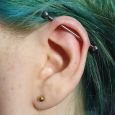 A horizontal industrial piercing on a girl with blue hair