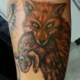 A fox with his prey tattooed on the leg