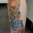 A colorful flower stretching along the side of the calf on scar tissue