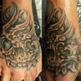 A hand tattoo with an organic, mutated skull